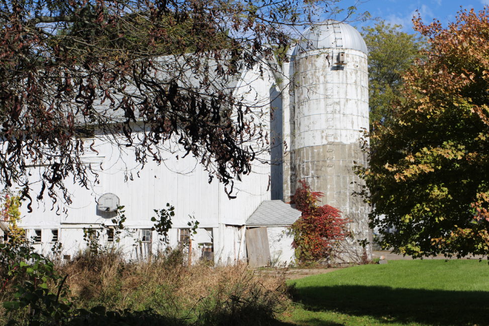 A big, white barn with silo attached.
